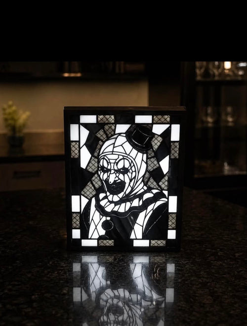 Black and white Art the Clown portrait with top hat and geometric border displayed in a black light-up frame