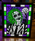 Beetlejuice portrait in green, purple, black and white with a stained-glass-style border displayed in a black light-up frame