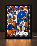 Illustrative CNS Customs light-up frame mockup of Moonlit Coastal Pottery Terrace, featuring cobalt-blue water and pottery, orange flowers, a crescent moon, and a slim black tabletop frame