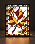Illustrative framed preview of golden maple leaf surrounded by burgundy bandana-style swirls in slim black tabletop frame