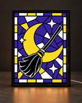 Black broom crossing a yellow crescent moon with white stars on purple mosaic stained-glass-style artwork inside slim black light-up frame; illustrative digital framed preview